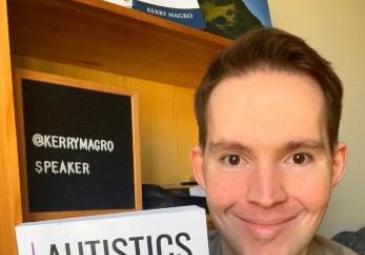 man holding up book "Autistics on Autism"