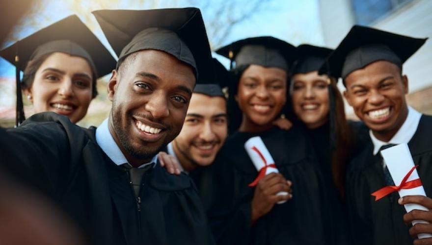 SIX BLACK STUDENTS IN GRADUATION ATTIRE SMILE