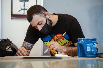 Student wearing a mask while painting with a brush