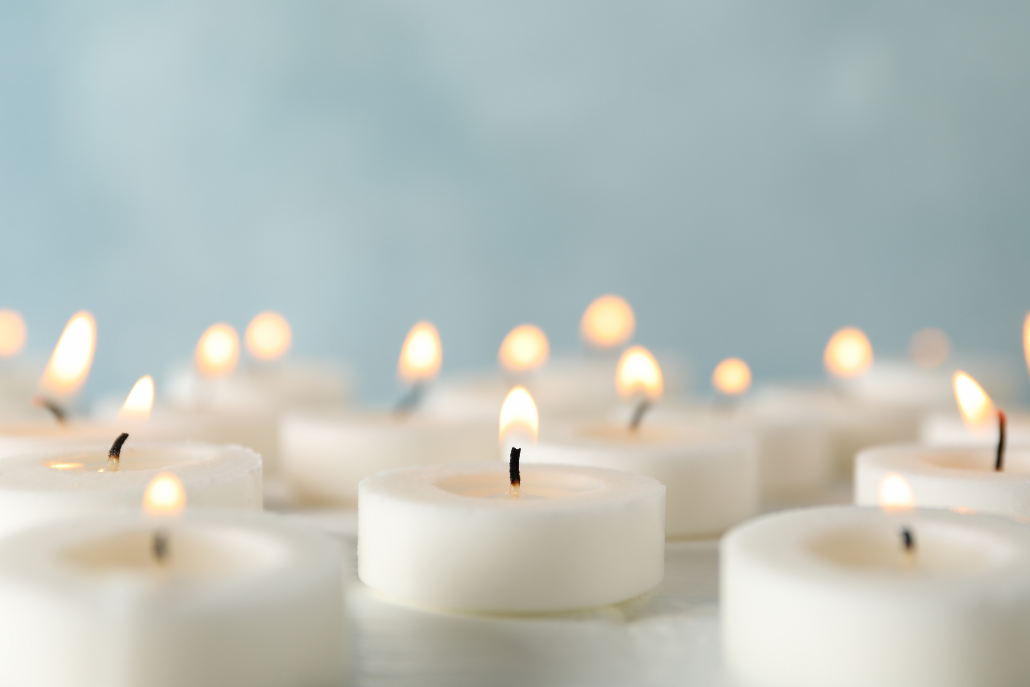 Group of burning candles against blue background, close up - stock photo GettyImages-1195555709