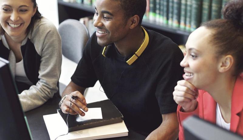 Three students looking at a computer monitor in the library.