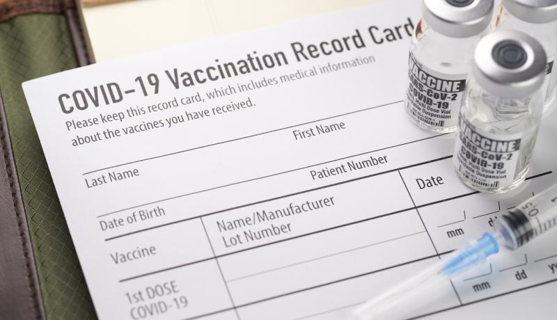 Covid 19%20vaccination%20record%20card%20with%20vials%20and%20syringe.%20 %20stock%20photo%20GettyImages 1289454645