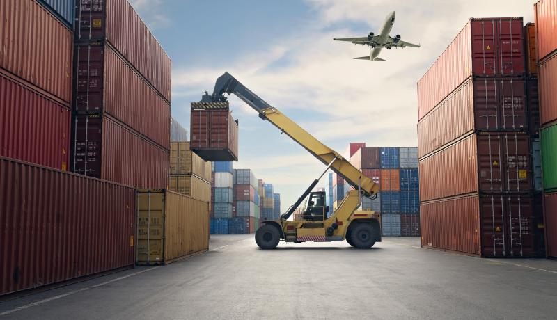 Airplane flying above container port. - stock photo GettyImages-1307002913