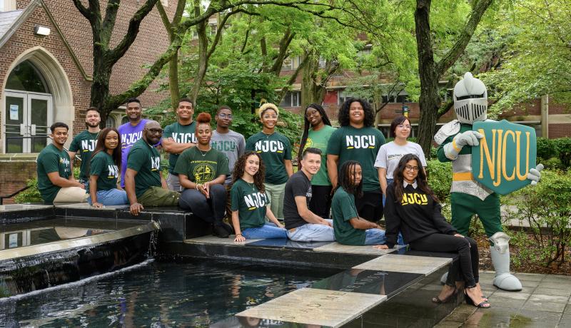 Students seated at fountain in front of Hepburn Hall with Gothic Knight mascot