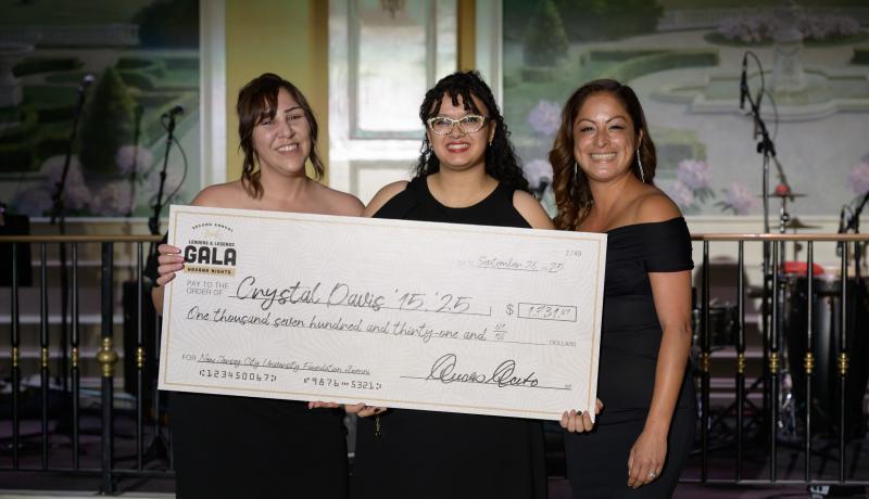 Alumna Crystal Davis receives a check from Nadia Tini and Cinthia Diaz at the NJCU Gala