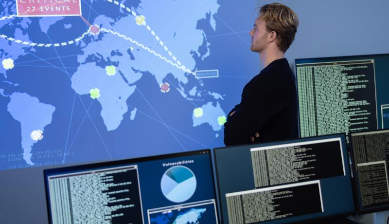 Back View in the Cyber Security Control Center Operator Working. Multiple Screens Showing Technical Data and Alerts. - stock photo
