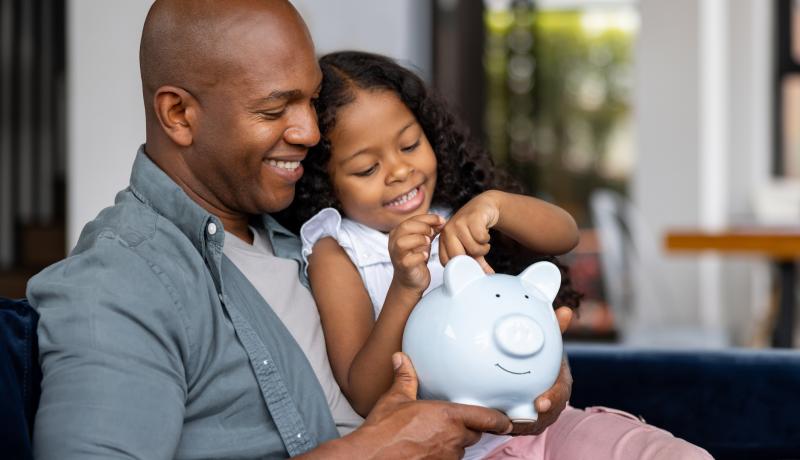 Father and daughter saving money in a piggybank - stock photo