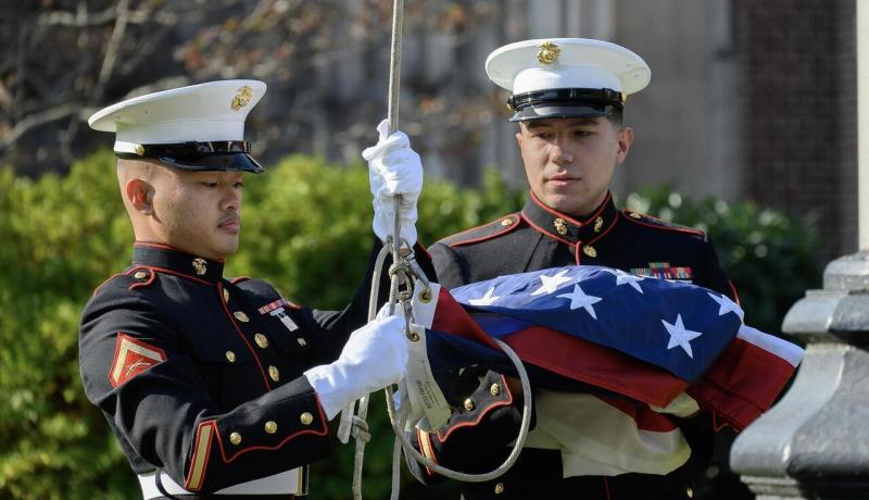 2 veterans raising the flag on the Hepburn Hall front lawn