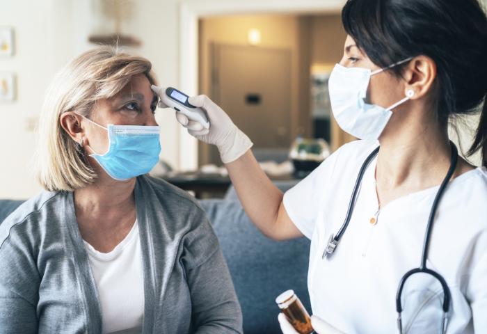 A woman has her temperature checked by a medical professional