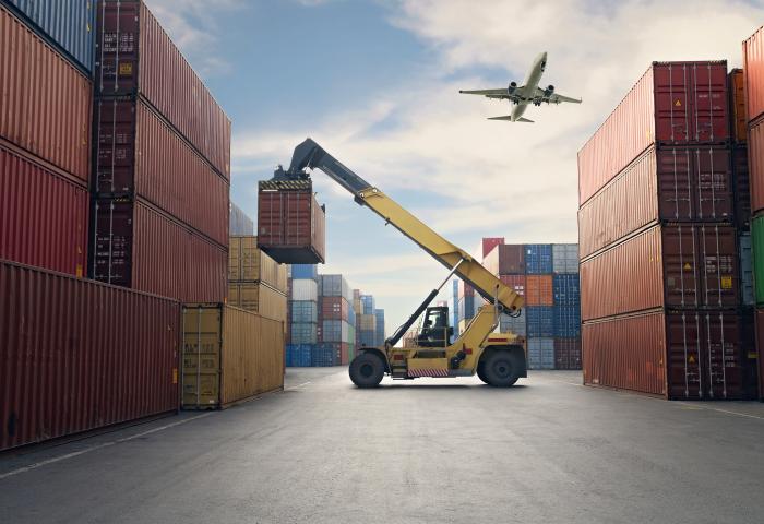 Airplane flying above container port. - stock photo GettyImages-1307002913
