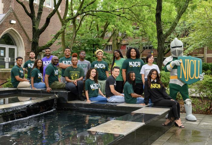 Students seated at fountain in front of Hepburn Hall with Gothic Knight mascot