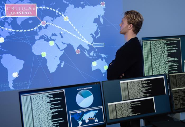 Back View in the Cyber Security Control Center Operator Working. Multiple Screens Showing Technical Data and Alerts. - stock photo