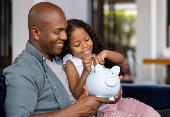 Father and daughter saving money in a piggybank - stock photo