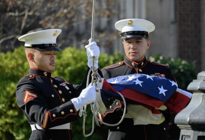 2 veterans raising the flag on the Hepburn Hall front lawn