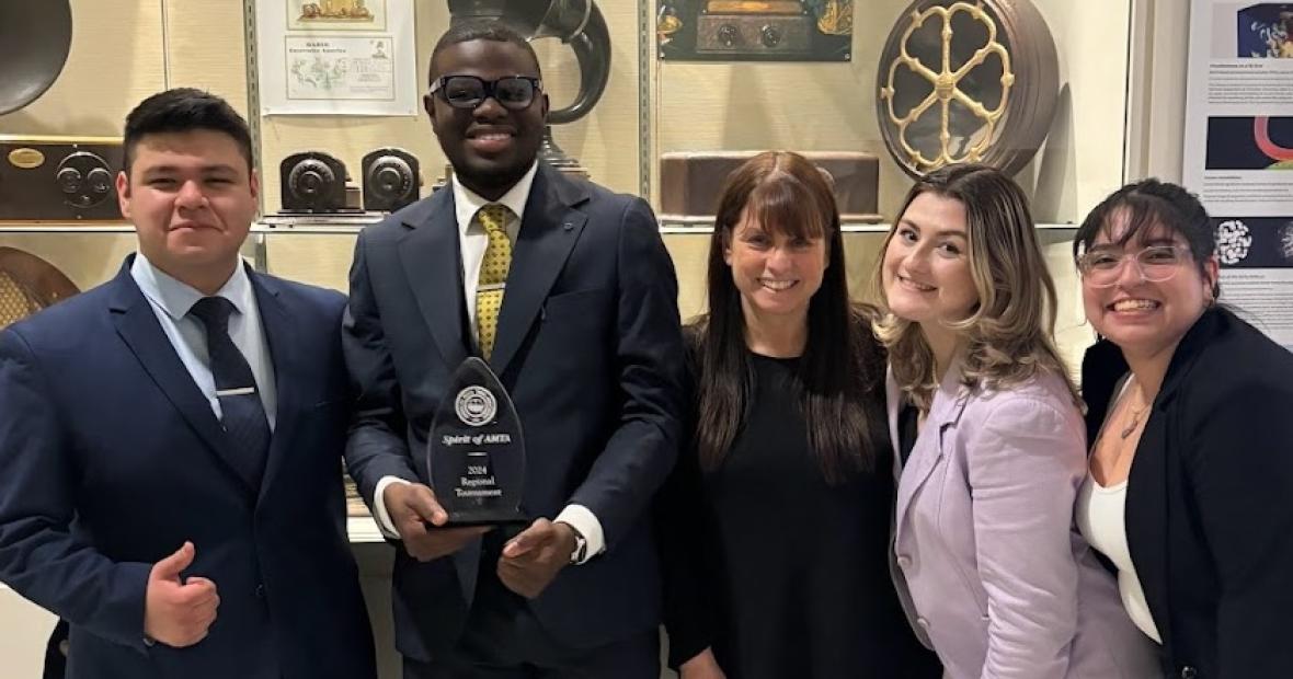 STUDENT WITH AWARD POSES WITH STUDENTS AND PROFESSOR