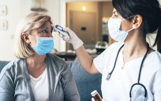 A woman has her temperature checked by a medical professional