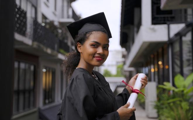 FEMALE GRADUATE IN GOWN WITH DIPLOMA