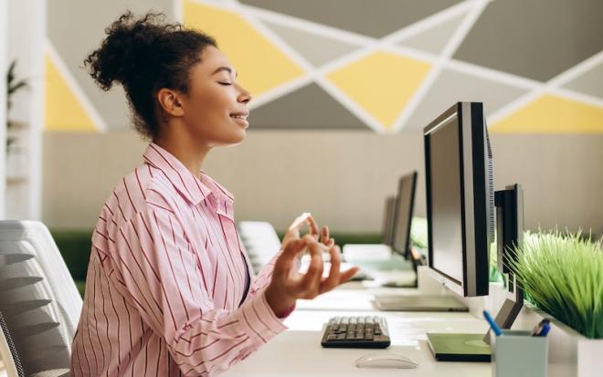 WOMAN MEDITATING AT WORK DESK