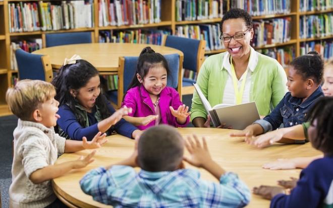 female teacher reading to students in library