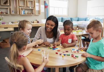 female teacher teaching young children at round table