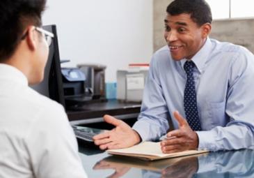Businessperson having a conversation with a younger person at a desk