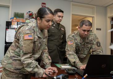 3 military students look on laptop