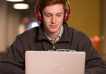 student at a laptop wearing headphones