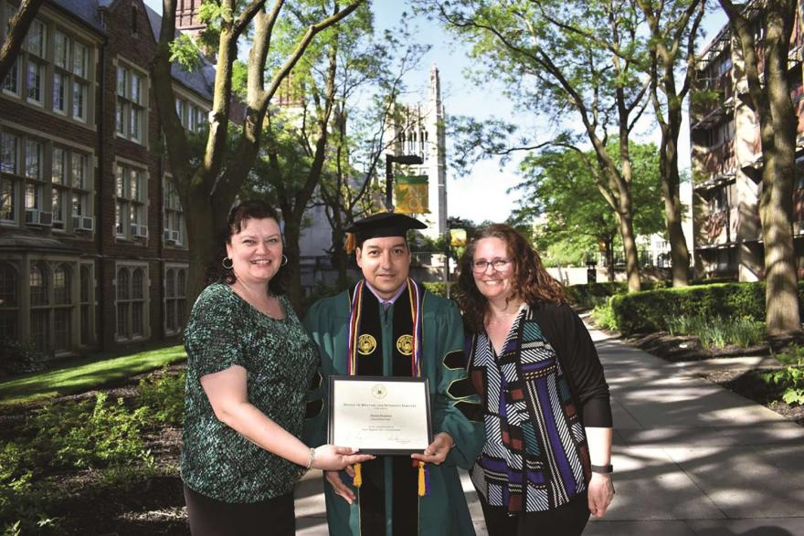 Veteran graduate poses outside with diploma.