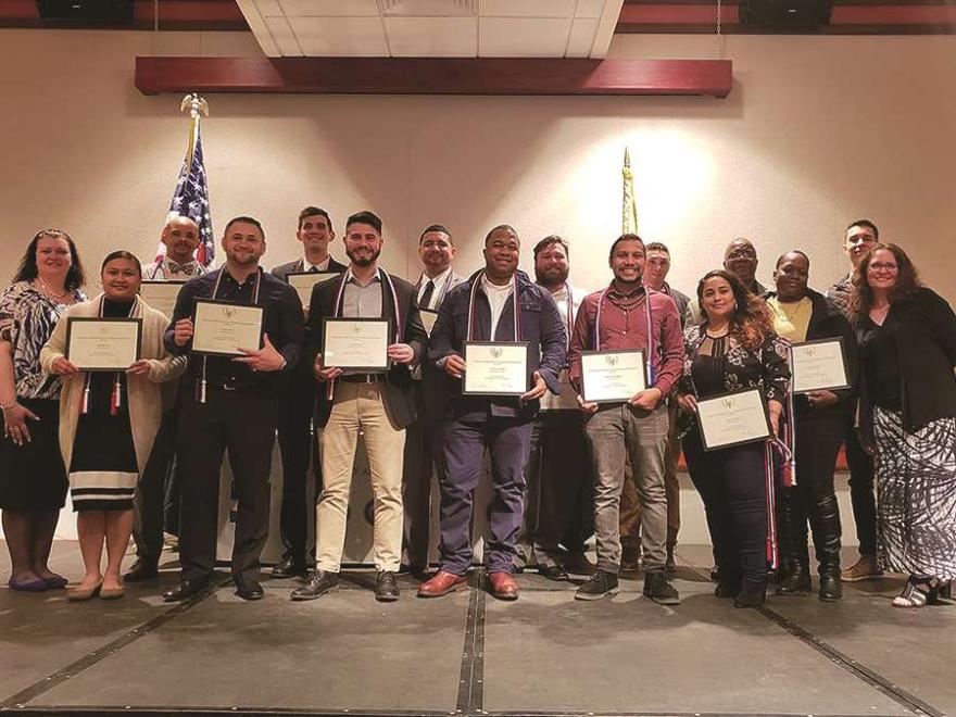 Veteran graduates pose with diplomas.