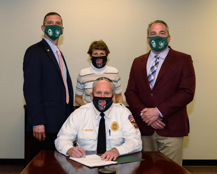 New Jersey Fire Marshal Richard Mikutsky (seated), Chair of the NJCU Fire Science Department Walter Nugent (left), Fire Science Program Assistant Anna Scanniello (middle), and Dean Dr. Michael Edmondson (right) at the signing ceremony.