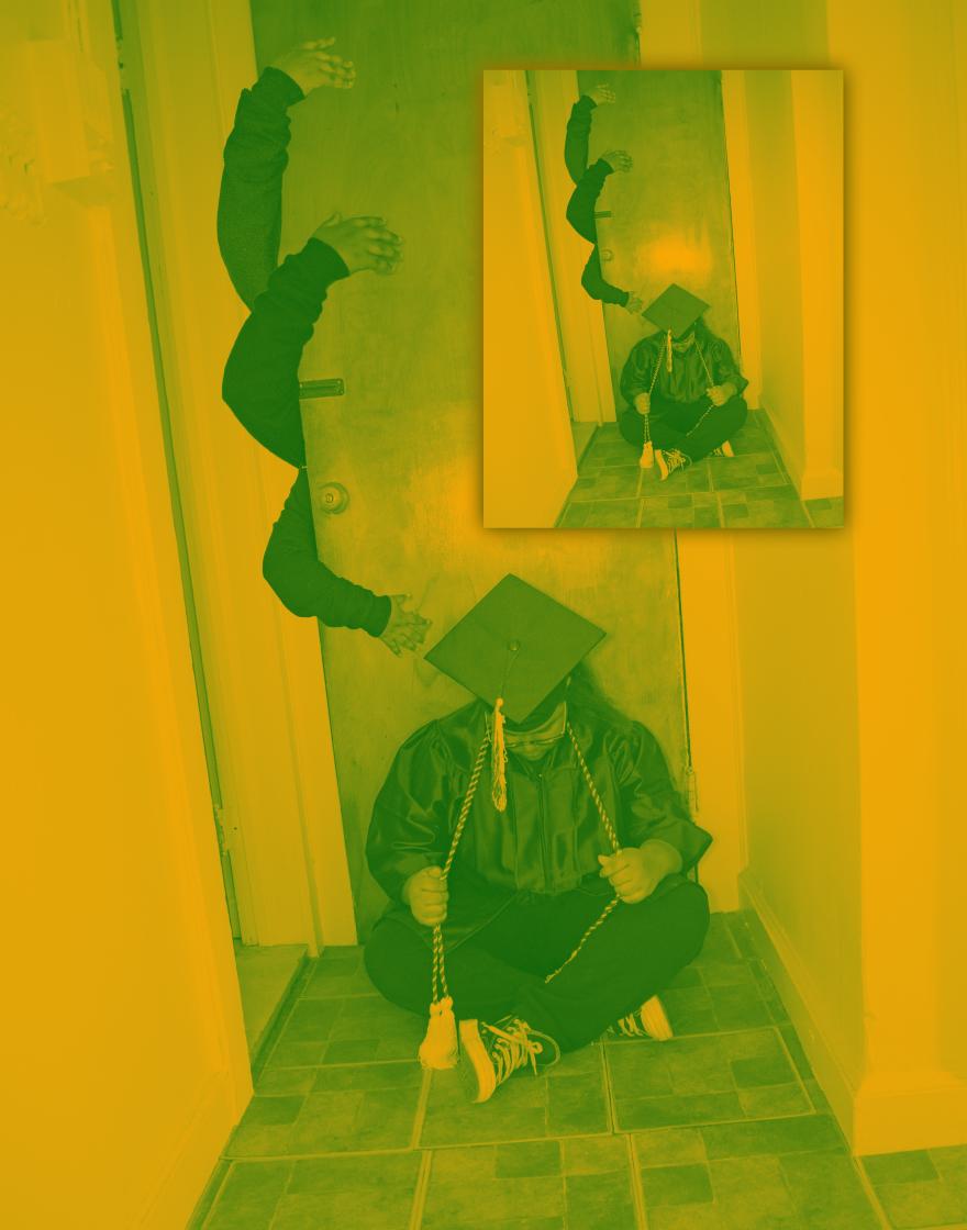 student in cap and gown sitting against a door with hand reaching out from behind it