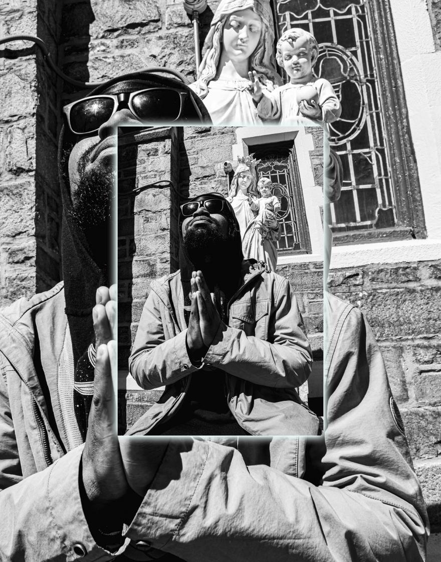 man in sunglasses stands in front of Virgin Mary