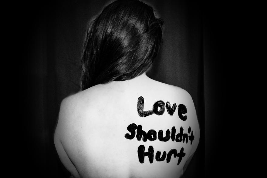 Person with words on their back that say, love shouldn't hurt