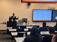man stands in front of classroom with large monitor