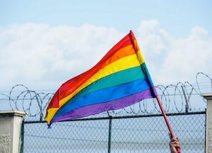PRIDE FLAG AGAINST BARRICADE FENCE