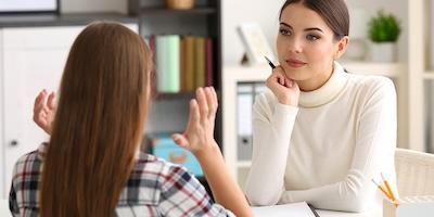 two women discuss at table
