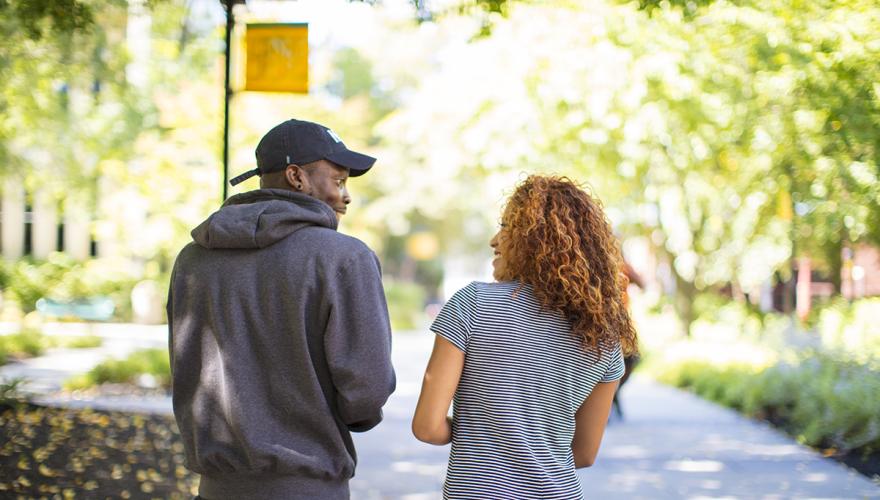 two students walking and talking on campus
