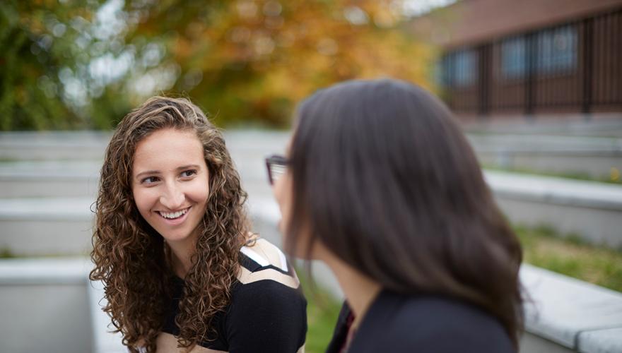two female students sitting and talking in the GSUB Patio