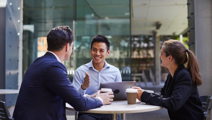 young professionals sitting at a table talking and having coffee