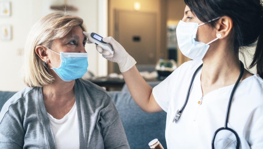 A woman has her temperature checked by a medical professional