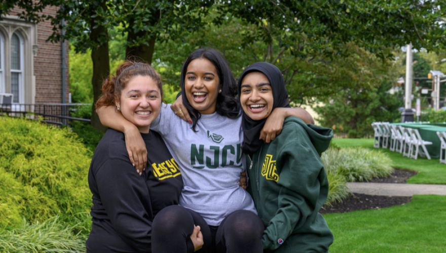 3 female students on campus hugging