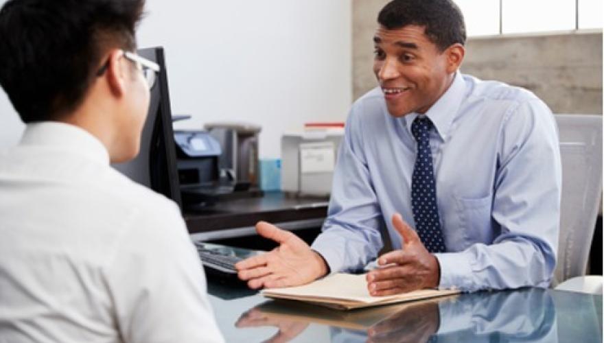 Businessperson having a conversation with a younger person at a desk