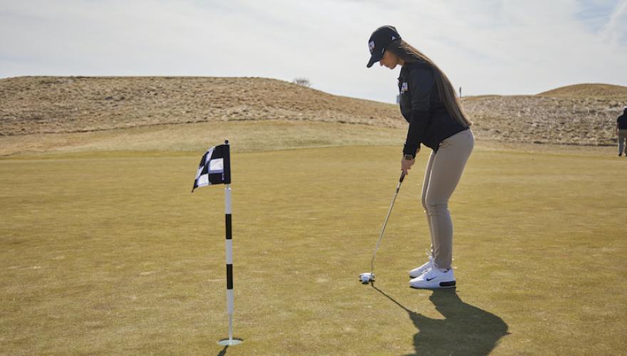 FEMALE PRACTICING GOLF