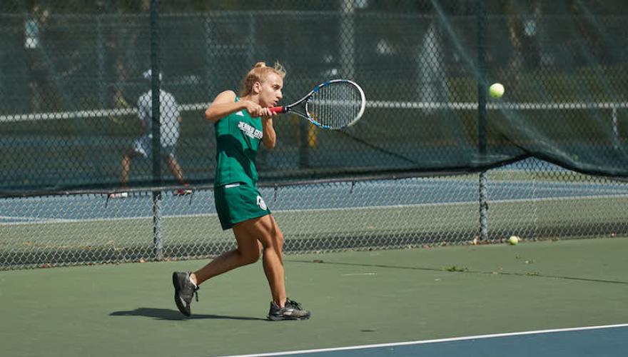 woman swinging tennis racquet towards ball