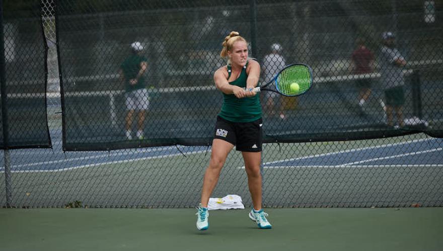 WOMAN SWINGING TENNIS RACQUET ON COURT