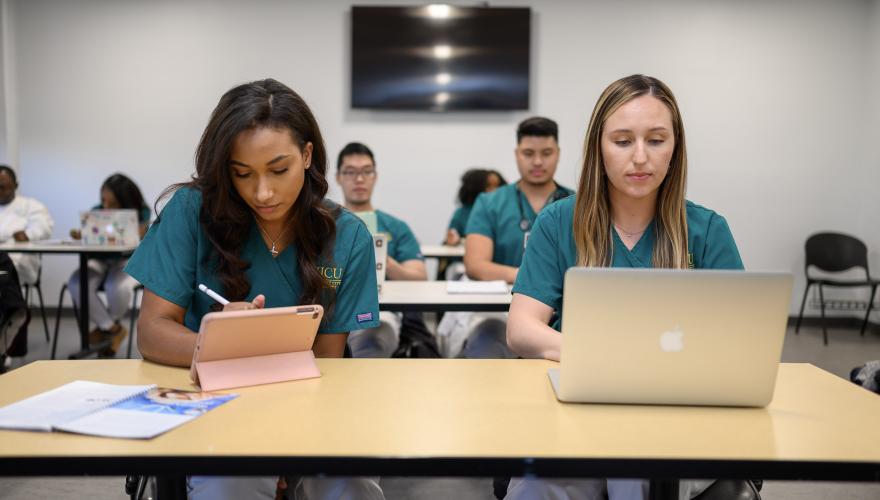 Nursing students at desk with iPad and MacBook