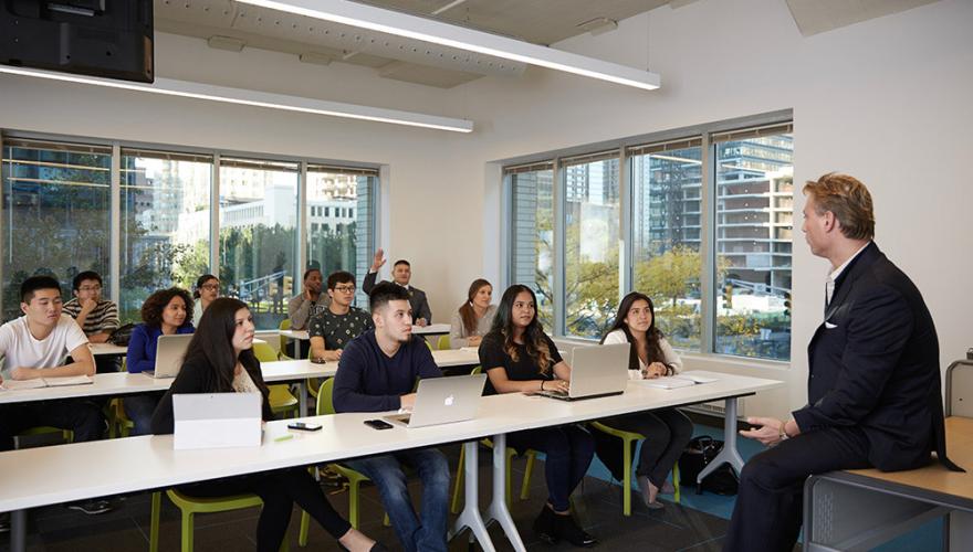 Teacher sitting on desk teaching class at the NJCU School of Business