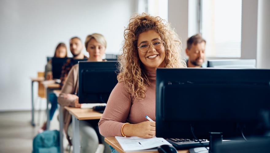 WOMAN IN COMPUTER CLASSROOM SMILING