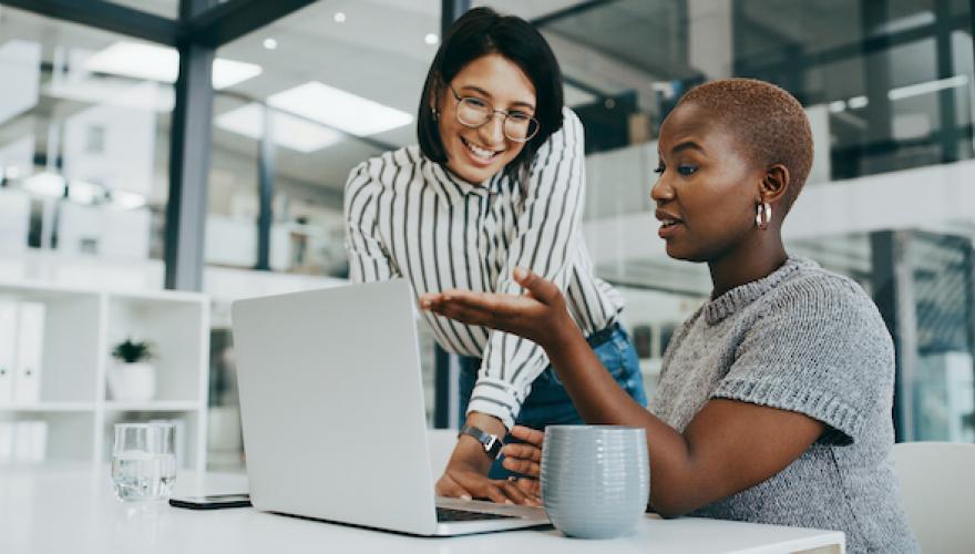 two women at a computer smiling