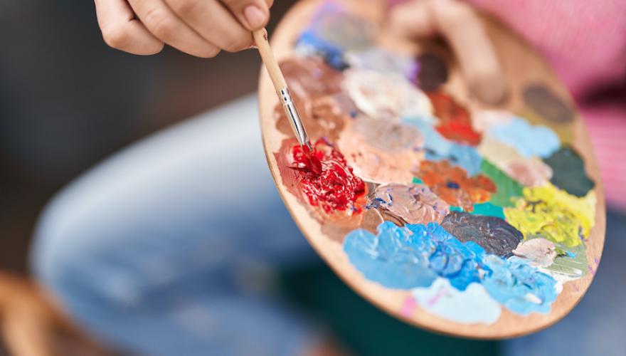 PAINT PALETTE WITH HAND AND PAINTBRUSH